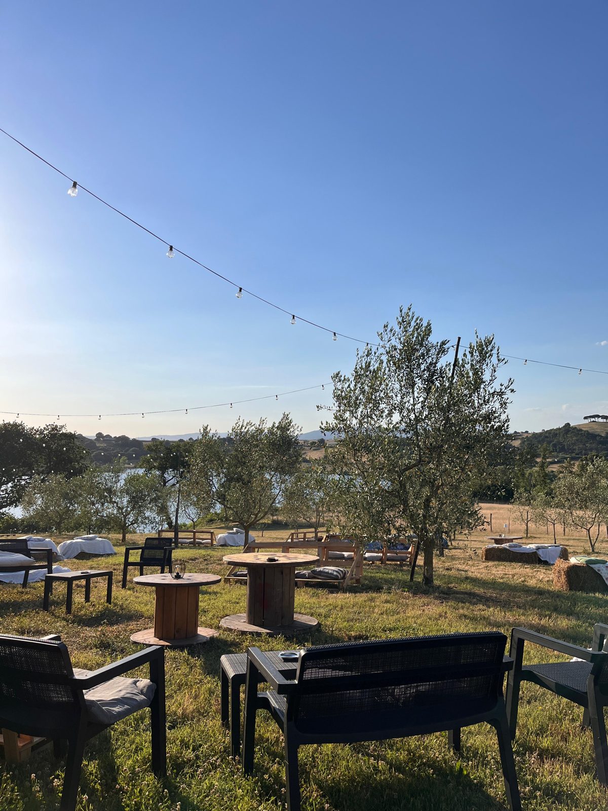 Il giardino di Frà Viaco la sera, con luci sospese e sedute affacciate sul Lago di Mezzano