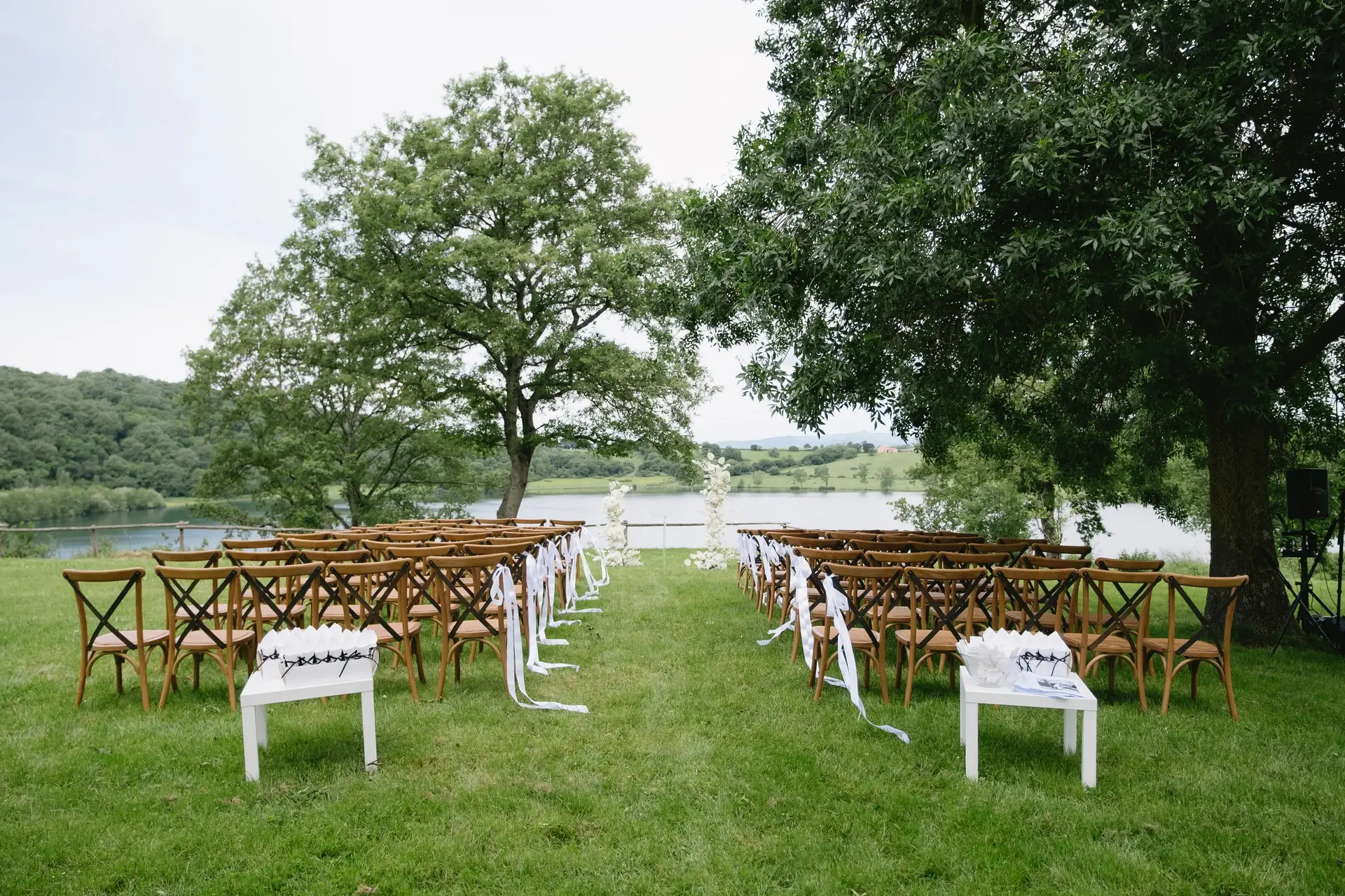 Rows of white chairs set on the lawn for a lakeside wedding ceremony at Frà Viaco, facing Lago di Mezzano