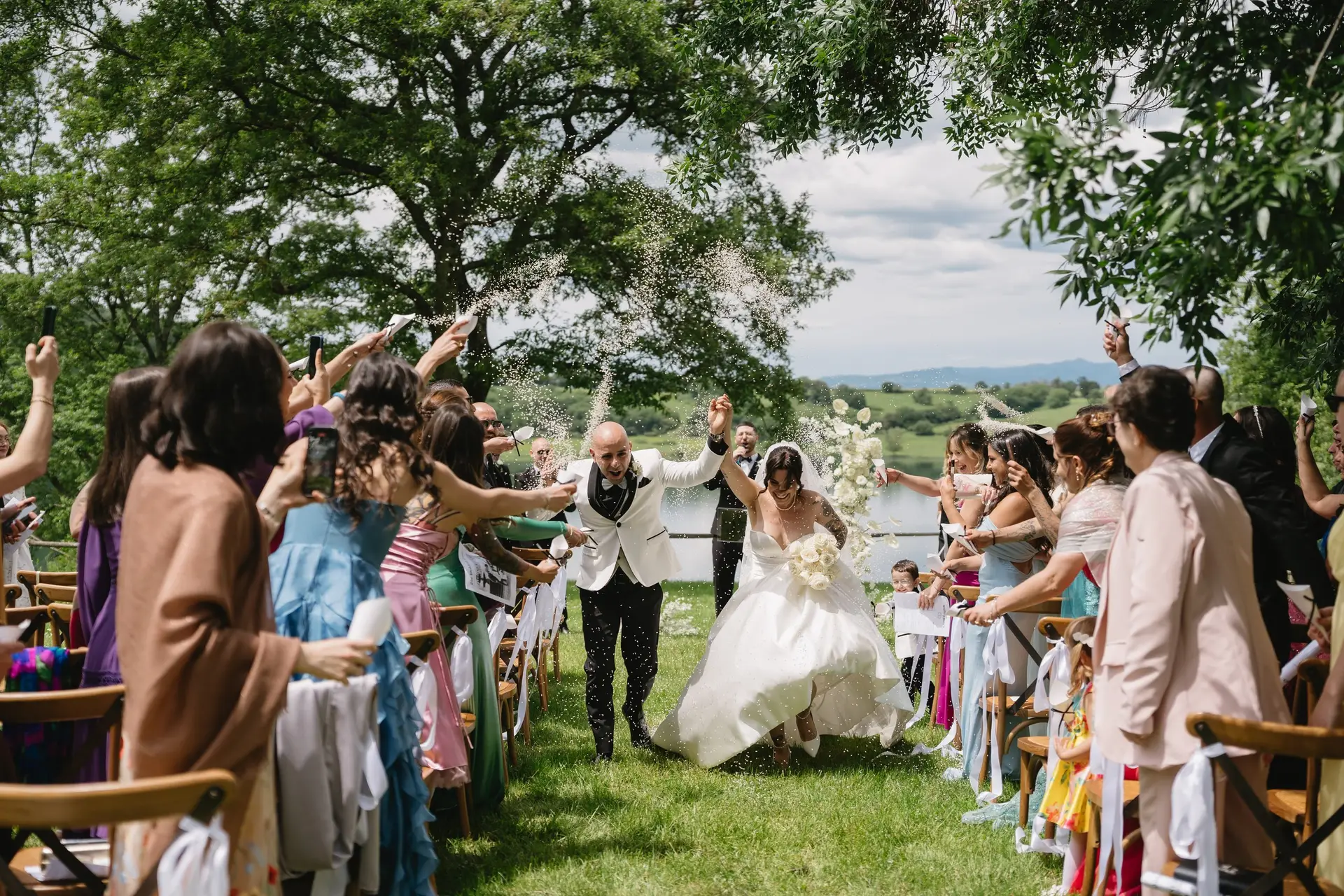 The newlyweds walk out among their guests under the great oak after the ceremony at Frà Viaco