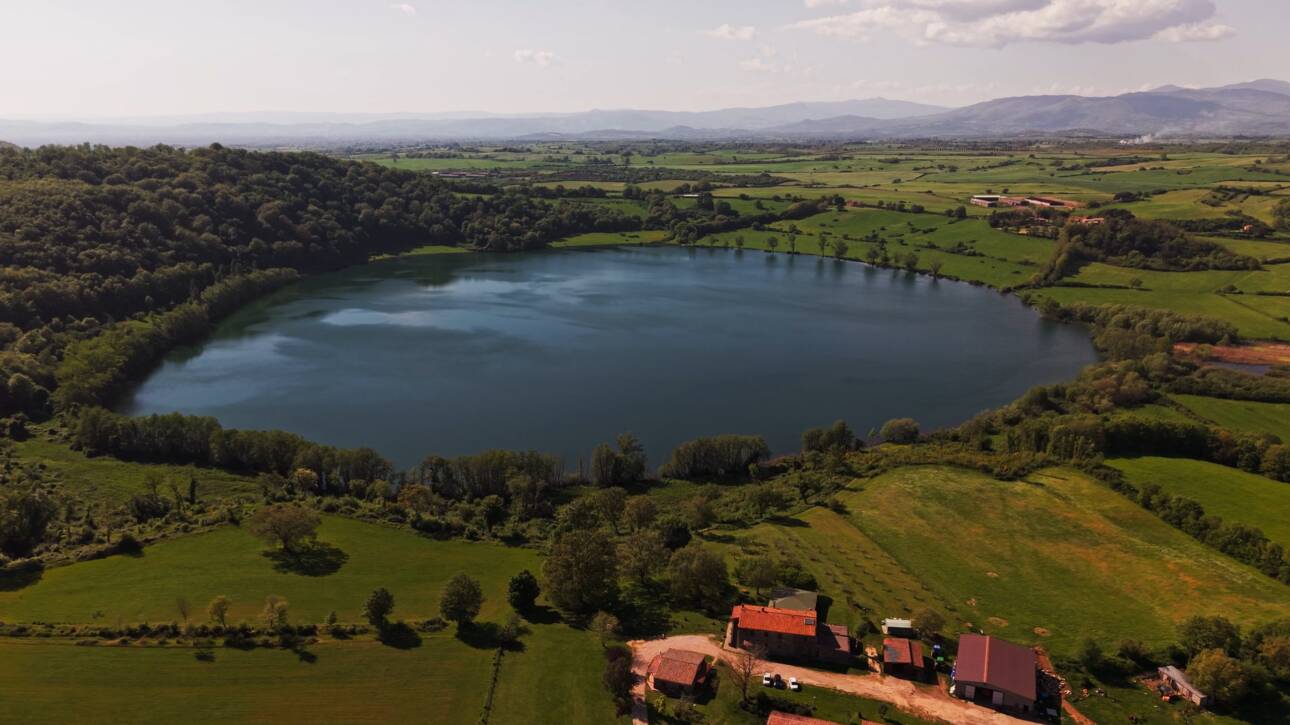 Il Lago di Mezzano visto dall'alto con la campagna dell'Alta Tuscia e i Monti Volsini sullo sfondo